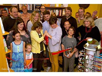 A crowd cutting a red ribbon at 2 Dandelions Bookshop